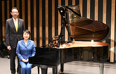 グランドピアノの横で記念撮影をする臼井清子さんと濱田市長