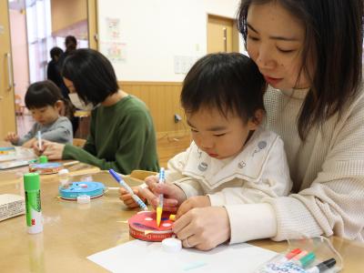 鬼のでんでん太鼓を作る親子の写真