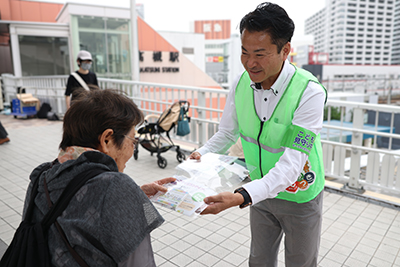 啓発リーフレットを通行人に手渡す市職員