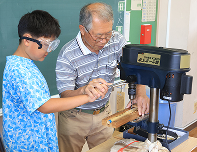 電動ドリルを使って篠笛作りをする児童