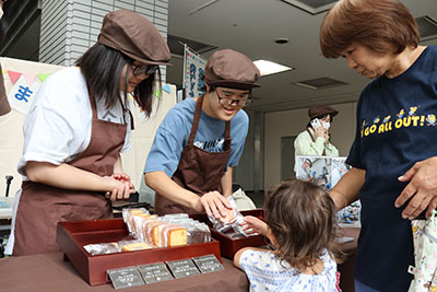 焼き菓子をスタッフに渡す市民