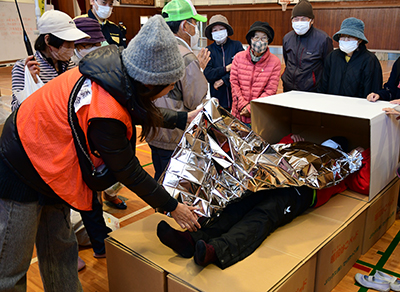 段ボールベッドを体験する訓練参加者