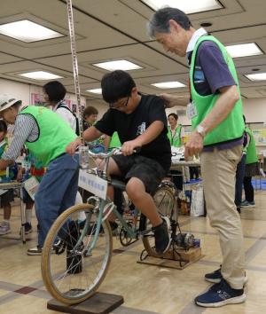たかつきエコ＆クリーンフェスタで自転車発電機の体験をする男の子