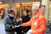 街頭啓発で啓発グッズを配る人とそれを受けとる家族