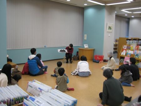 児童書コーナーで、子どもや保護者に絵本の読み聞かせをしている写真