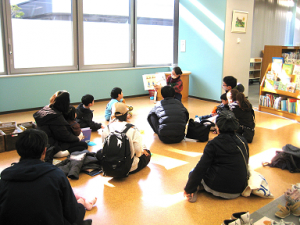 児童書コーナーで、子どもや保護者に絵本の読み聞かせをしている写真